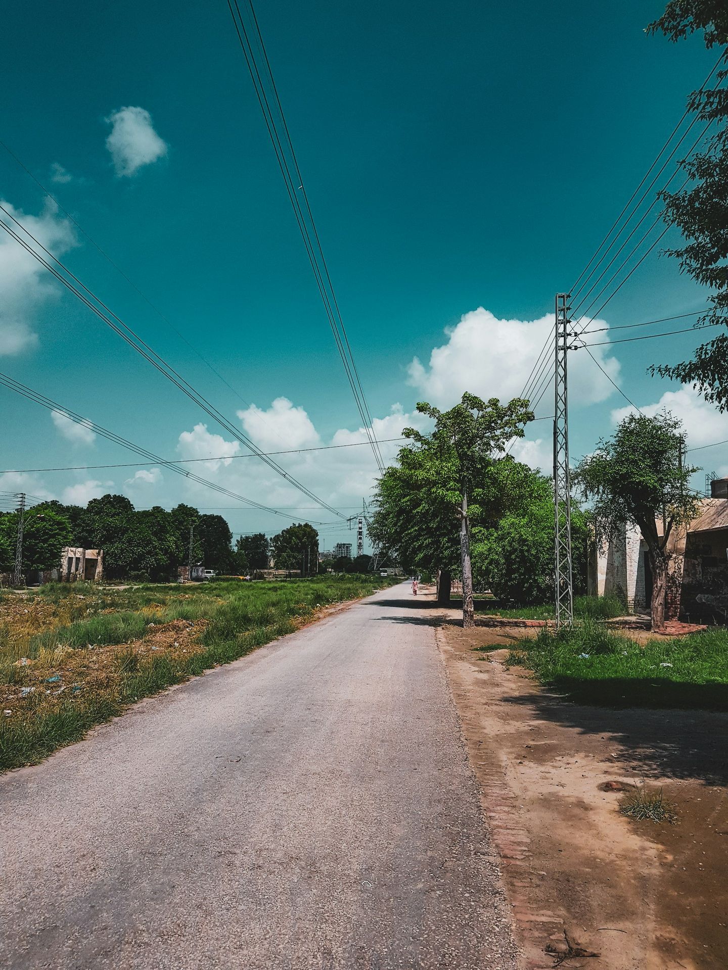 a dirt road with power lines on either side of it